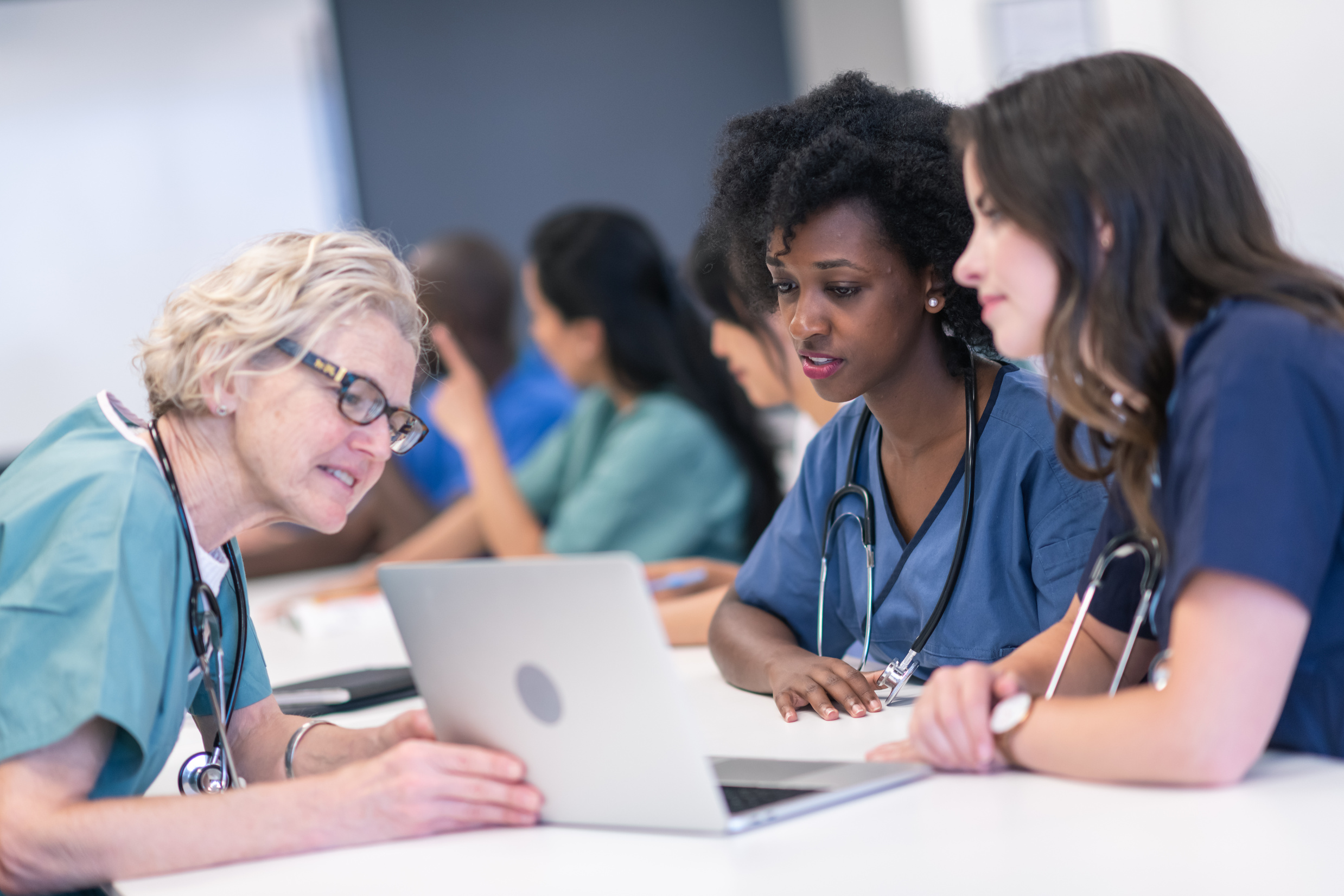 Senior female lecturer assists medical students during class